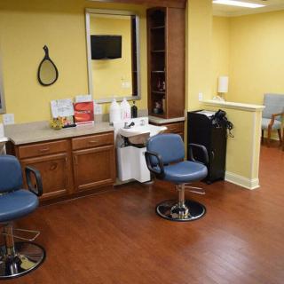 An interior view of a hair salon with chairs arranged around mirrors and a small waiting area.