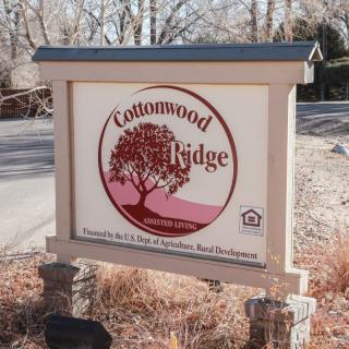 A sign for Cottonwood Ridge with a tree logo, located by the roadside.