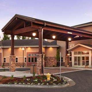 A well-lit hotel entrance with a covered driveway and landscaped surroundings at dusk.