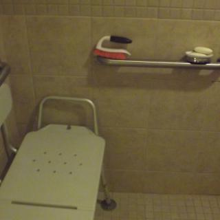 Accessible bathroom with a shower chair and grab bar.