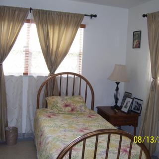 A cozy bedroom with a single bed, nightstand, and curtains.