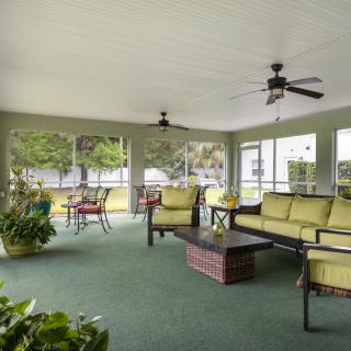 A spacious indoor patio with comfortable seating, green carpeting, and ceiling fans.