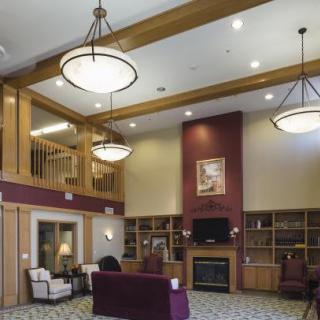 A cozy lobby area with comfortable furniture, warm lighting, and a fireplace surrounded by bookshelves.
