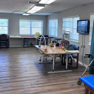 A spacious therapy room equipped for rehabilitation activities, featuring natural light from the windows.
