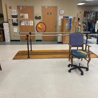 A rehabilitation room equipped with parallel bars for physical therapy exercises, accompanied by seating arrangements.