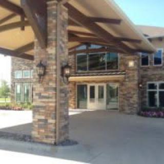 The entrance of a modern brick building with large windows and a covered walkway.