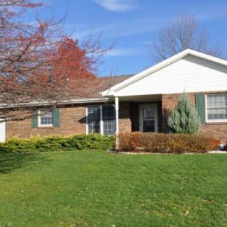 A suburban brick house with a well-maintained front lawn and trees.