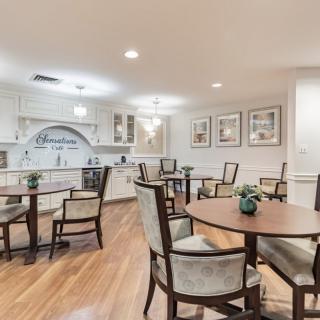 A modern kitchen and dining area with round tables and upholstered chairs on wooden flooring.
