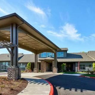A modern building with a covered entrance and landscaped surroundings.