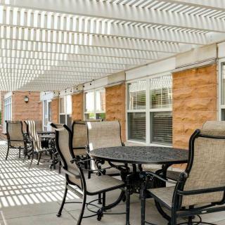 A sunlit outdoor patio area with tables and chairs under a pergola.