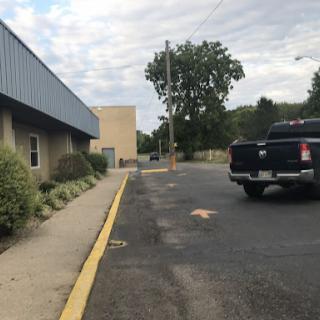 A view of a parking lot alongside a building with a truck parked on the road.