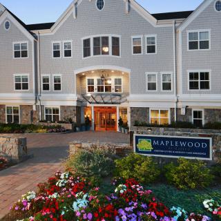 A front view of a building with an entrance, surrounded by well-maintained landscaping and colorful flowers.