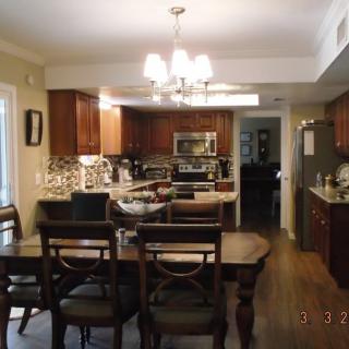A modern kitchen and dining area with wooden cabinets, a central dining table, and a chandelier.
