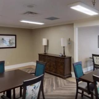 A modern dining room with tables and chairs, decorated with artwork and ambient lighting.