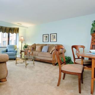 A cozy living room with a sofa, chairs, and a dining area under soft lighting.