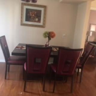 A cozy dining area with a table set for four, adorned with a decorative centerpiece and a painting on the wall.