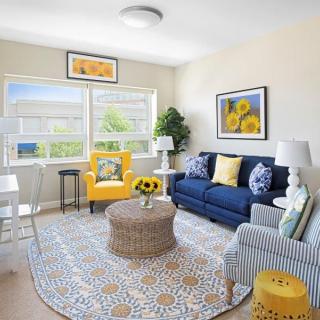 Bright living room featuring a blue sofa and yellow accents, filled with natural light.