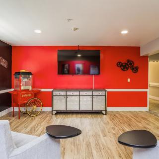 A modern living room entertainment area with a vibrant red accent wall, featuring a large TV and a vintage popcorn machine.