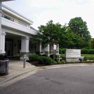 A view of a modern building with surrounding greenery and a street sign.