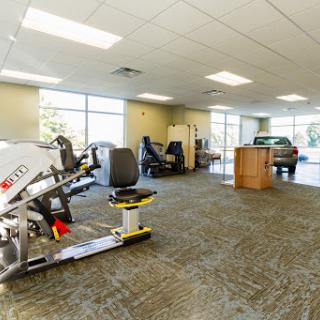 A spacious rehabilitation gym equipped with various exercise machines, designed for physical therapy and fitness.