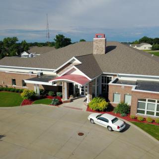 Aerial view of a building with a car parked in the driveway and landscaped surroundings.