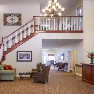 Spacious lobby with elegant staircase and chandelier lighting.