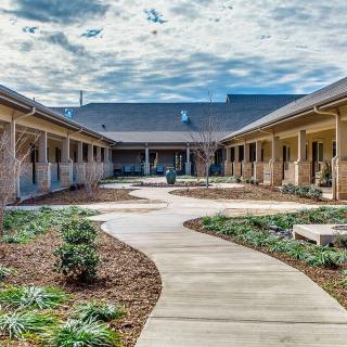 A serene courtyard with a curved pathway and landscaping under a partly cloudy sky.