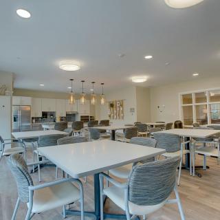 A modern dining area with an open kitchen, featuring contemporary tables and chairs.