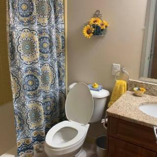 A well-decorated bathroom featuring a colorful shower curtain, sunflowers wall decor, and neatly arranged towels.