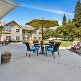 A spacious outdoor patio with a table, chairs, and an umbrella, set against a residential building.