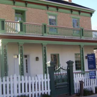 A two-story house with green accents and a white picket fence.