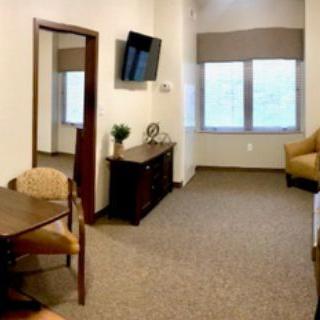 A cozy room with a television, seating area, and large windows.