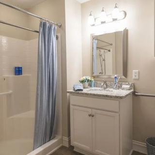 A modern bathroom with a vanity, mirror, and shower area.