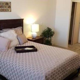 A cozy bedroom with a neatly made bed and warm lighting.