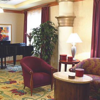 A cozy living room interior with a piano, comfortable seating, and soft lighting.