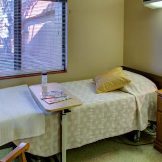 A clean and well-lit hospital patient room with a bed and a small table.