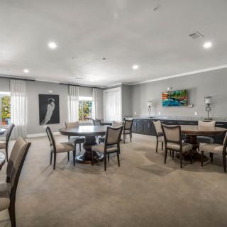 A spacious and modern dining area with multiple tables and chairs, featuring large windows and elegant artwork.