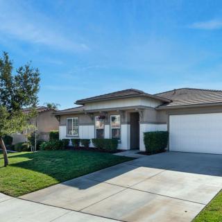 A suburban single-story house with a well-kept front yard and a driveway leading to the garage.
