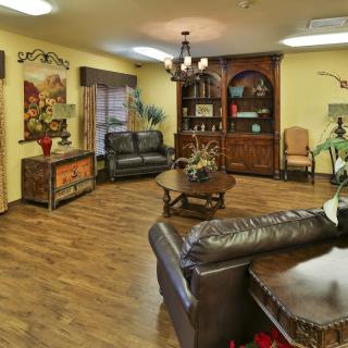 A cozy living room with leather sofas, wooden flooring, and a decorative bookshelf.