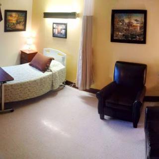 A cozy and well-decorated room featuring a single bed, a comfortable chair, and artistic wall decor.