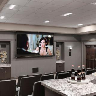 A cozy home theater setup with comfortable seating, a large screen, and refreshments on the counter.