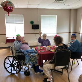 Elderly individuals gathered around a table, enjoying a celebration with party hats.