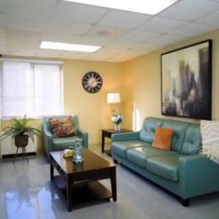 A modern living room with teal sofas, a wooden coffee table, and decorative artwork on the wall.