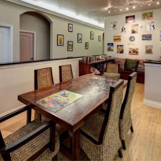 A cozy dining area with a wooden table and wicker chairs, adorned with a gallery wall of various artworks.