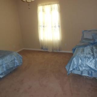 A minimalist bedroom featuring two twin beds with blue bedding and a carpeted floor.
