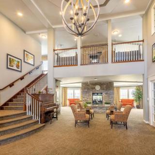 Spacious living room with elegant decor, featuring a grand staircase and modern chandelier.