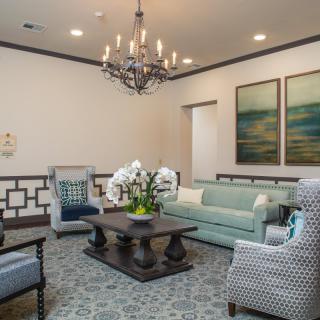 A stylish living room featuring elegant furniture, a chandelier, and modern artwork.
