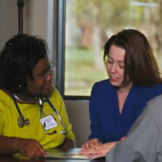 A healthcare professional and a colleague discussing documents in an office setting.
