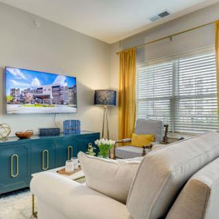 A stylish and cozy living room featuring a modern sofa, vibrant curtains, and a large television for entertainment.
