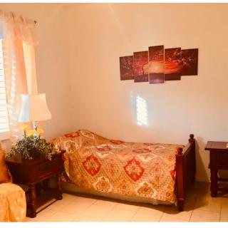 A cozy bedroom with a single bed and colorful quilt, complemented by a nightstand and lamp.